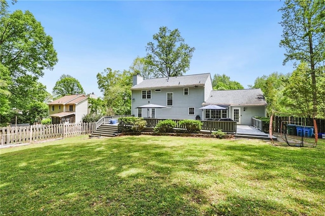 rear view of property with fence, a yard, a chimney, and a deck