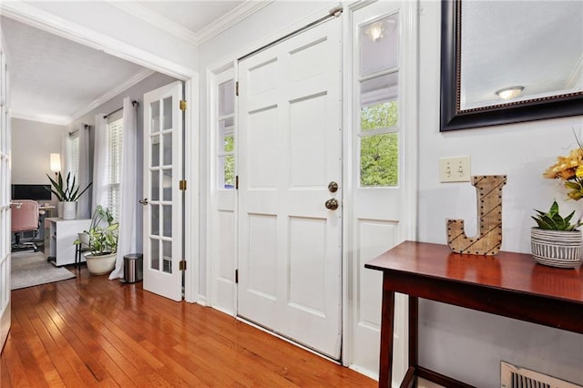 entryway with visible vents, ornamental molding, and hardwood / wood-style floors