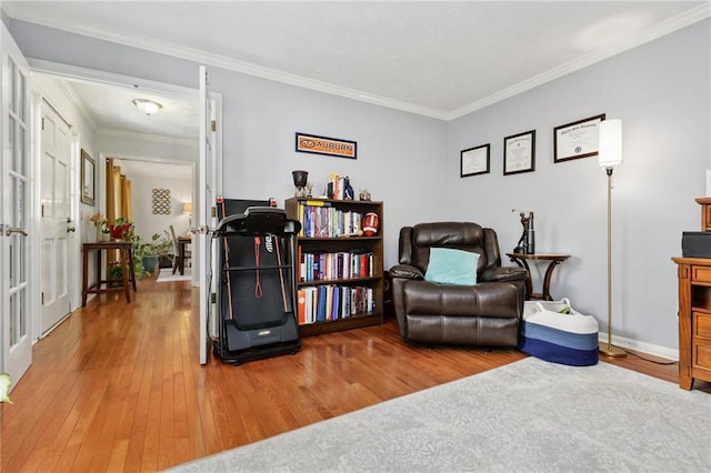 sitting room featuring wood-type flooring, baseboards, and crown molding