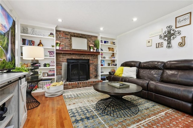living room with ornamental molding, a brick fireplace, wood finished floors, recessed lighting, and built in shelves