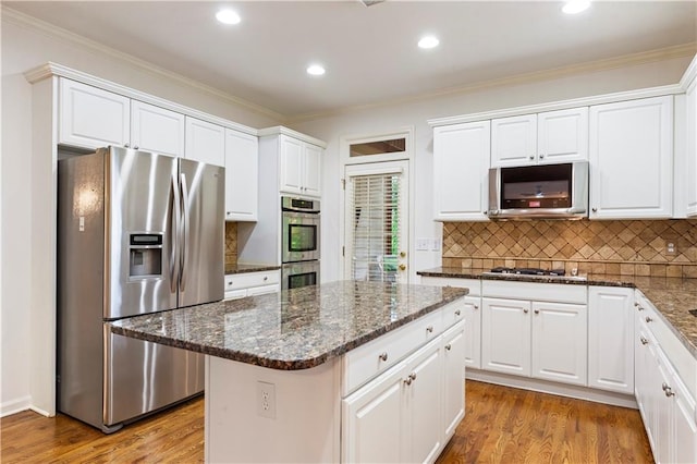 915 Summer Wind Pl, Roswell, GA 30075 - kitchen featuring appliances with stainless steel finishes, white cabinetry, wood finished floors, a kitchen island, and backsplash