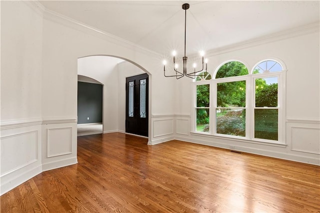 915 Summer Wind Pl, Roswell, GA 30075 - spare room featuring a chandelier, arched walkways, a decorative wall, healthy amount of natural light, and wood finished floors