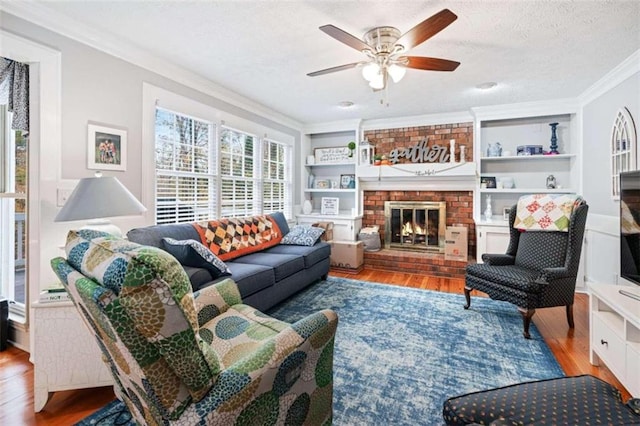 living room with a textured ceiling, crown molding, light hardwood / wood-style flooring, built in features, and a fireplace