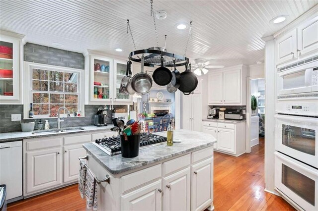 kitchen with white appliances, ceiling fan, sink, white cabinets, and light hardwood / wood-style floors