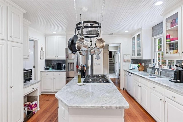 kitchen with white cabinetry, a center island, sink, tasteful backsplash, and light hardwood / wood-style floors