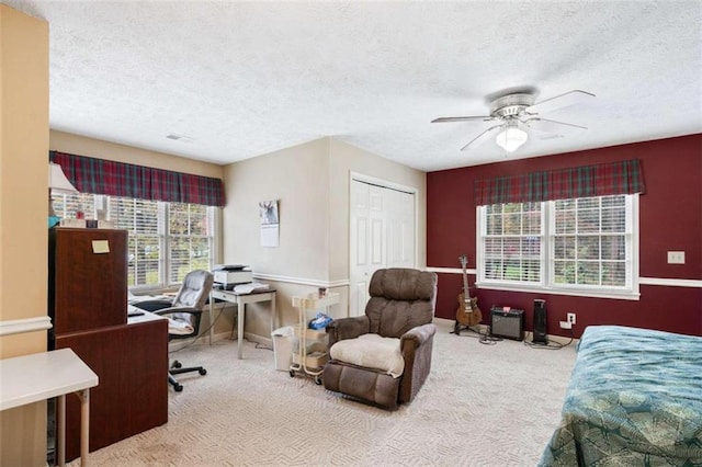 carpeted bedroom featuring multiple windows, ceiling fan, a closet, and a textured ceiling