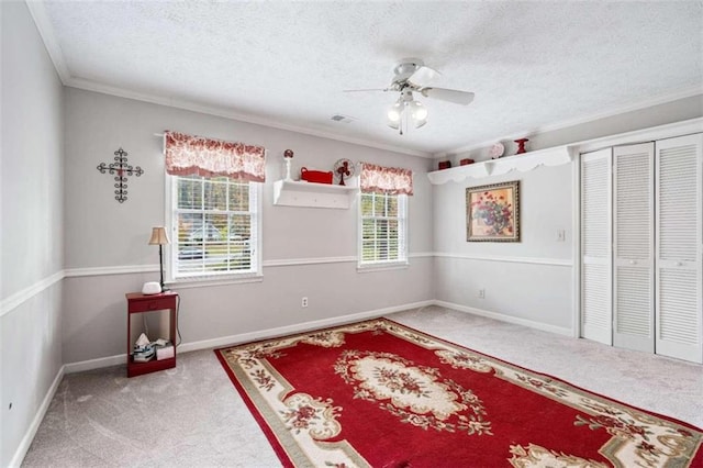 carpeted bedroom featuring a closet, ceiling fan, crown molding, and a textured ceiling