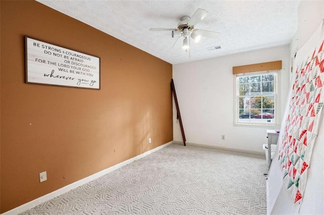 unfurnished bedroom with ceiling fan, light carpet, and a textured ceiling