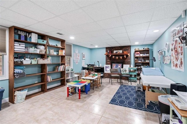 rec room featuring tile patterned floors and a drop ceiling