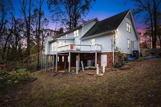 back house at dusk with cooling unit and a deck