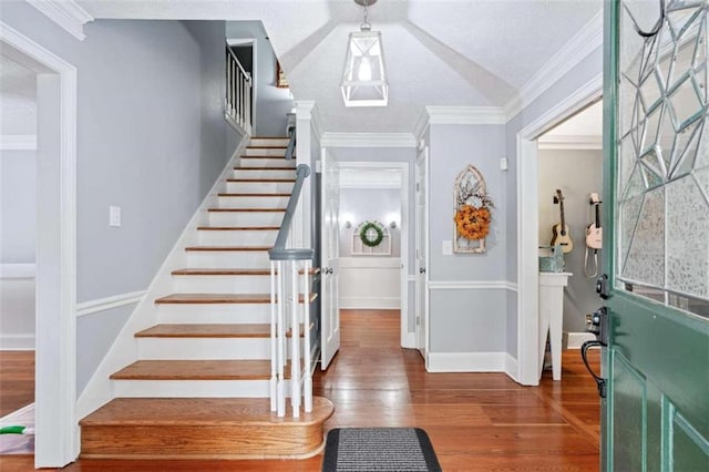 foyer with dark hardwood / wood-style flooring, crown molding, and vaulted ceiling