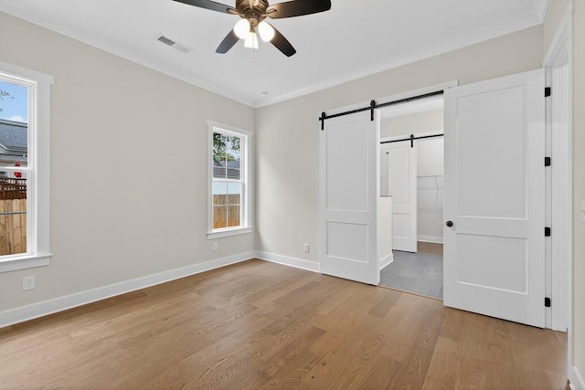 305 Milledge Ave, Monroe, GA 30655 - unfurnished bedroom featuring a barn door, light wood finished floors, crown molding, and ceiling fan