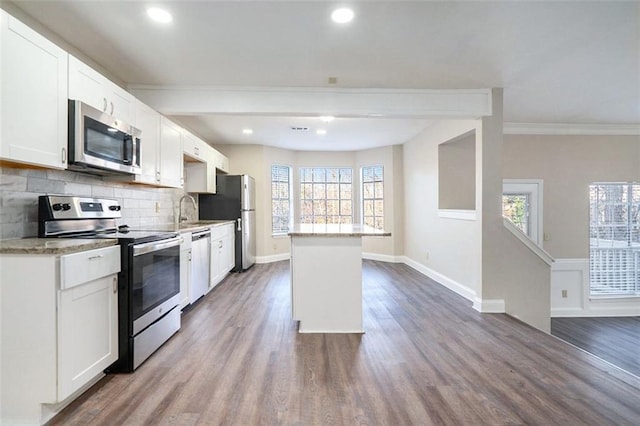 kitchen featuring backsplash, stainless steel appliances, sink, wood-type flooring, and white cabinets