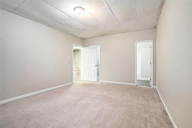 carpeted spare room featuring a drop ceiling