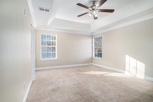 unfurnished room with a tray ceiling, ceiling fan, light colored carpet, and ornamental molding