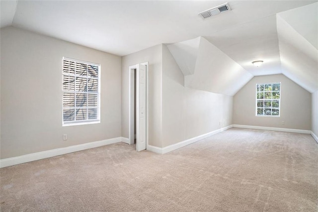 bonus room with light carpet and vaulted ceiling