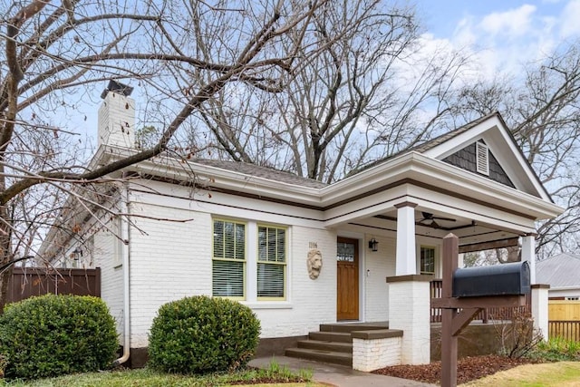 view of front facade with a chimney, fence, and brick siding