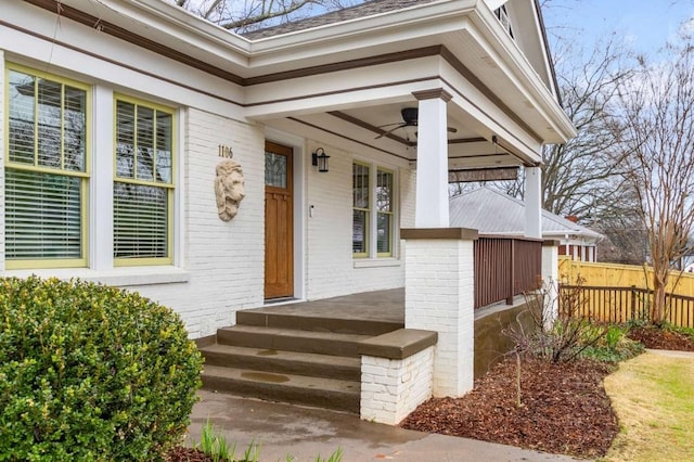 entrance to property featuring covered porch, ceiling fan, and brick siding