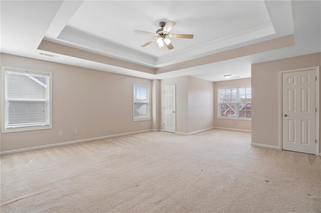 spare room with ceiling fan, baseboards, and a tray ceiling