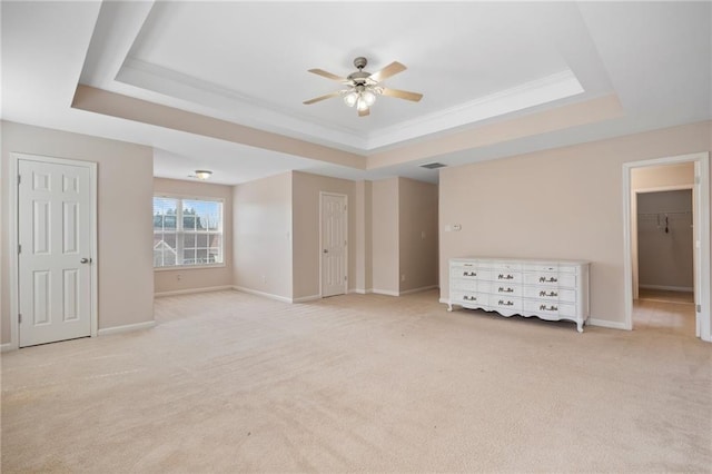 interior space with light carpet, baseboards, a raised ceiling, and ceiling fan