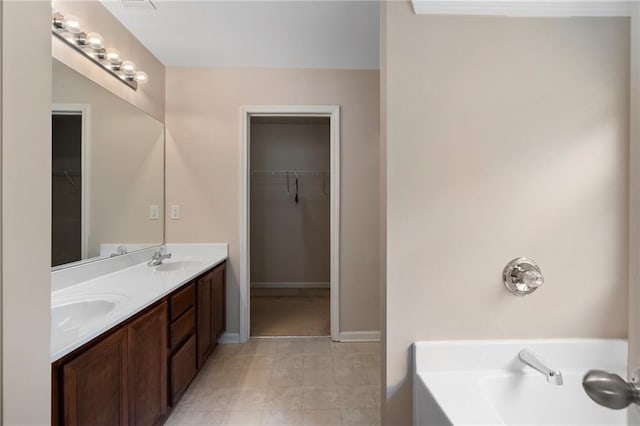 bathroom with double vanity, a tub, a walk in closet, and a sink