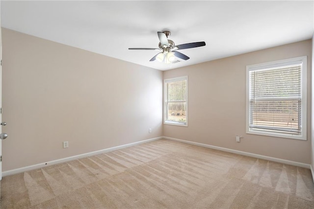 spare room featuring baseboards, light carpet, and ceiling fan