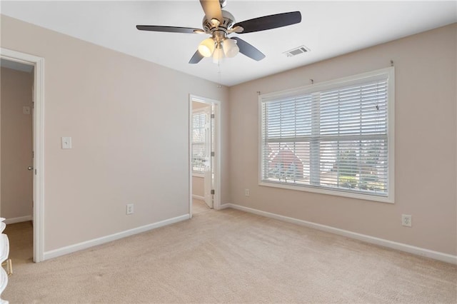 interior space with light carpet, visible vents, baseboards, and a ceiling fan