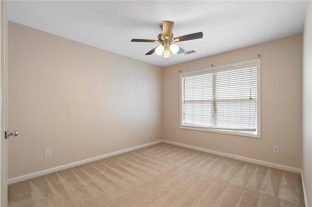 unfurnished room with visible vents, baseboards, light colored carpet, and a ceiling fan