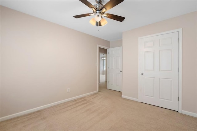 unfurnished bedroom featuring light colored carpet, baseboards, and ceiling fan