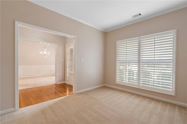 unfurnished room featuring visible vents, baseboards, carpet, a chandelier, and ornamental molding