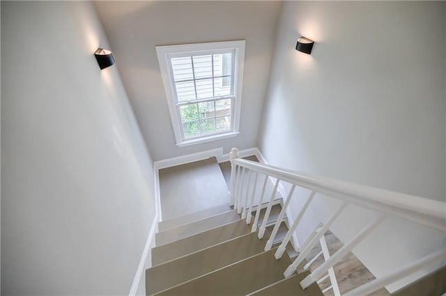 staircase featuring baseboards and wood finished floors