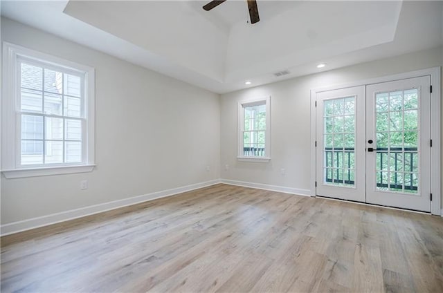 empty room featuring baseboards, ceiling fan, wood finished floors, a tray ceiling, and french doors