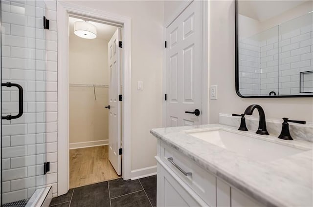 full bathroom featuring a stall shower, baseboards, tile patterned floors, a spacious closet, and vanity