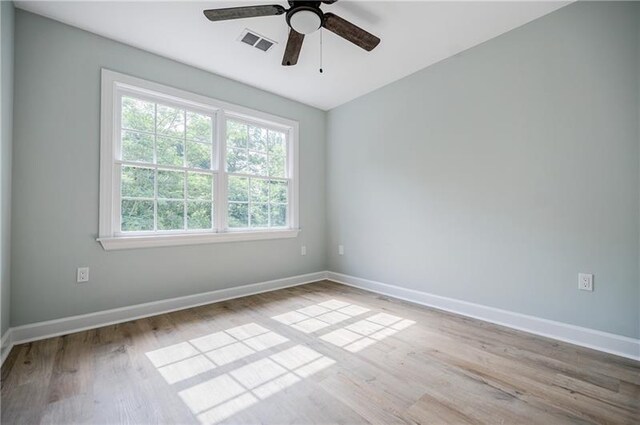 unfurnished room featuring a ceiling fan, baseboards, visible vents, and wood finished floors