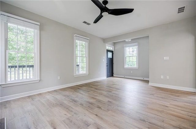 empty room with light wood finished floors, baseboards, and visible vents