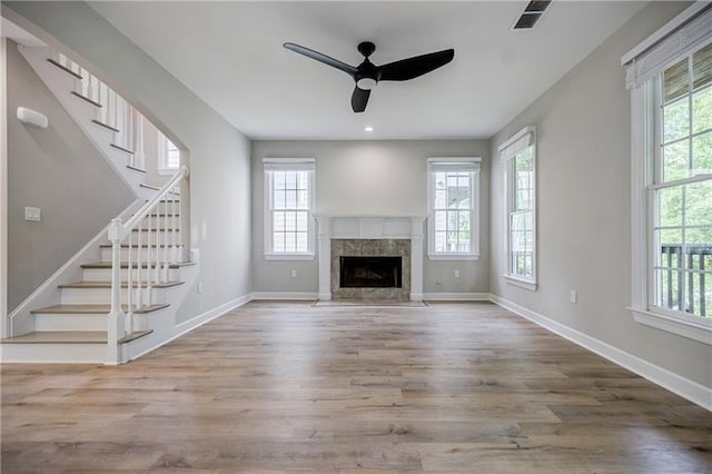 unfurnished living room with stairs, wood finished floors, visible vents, and baseboards