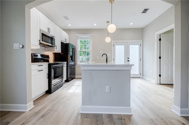 kitchen featuring arched walkways, appliances with stainless steel finishes, an island with sink, and visible vents