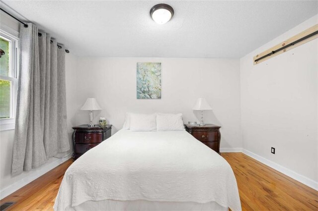 2021 Sherwood Dr SE, Marietta, GA 30062 - bedroom featuring wood finished floors, a barn door, and baseboards