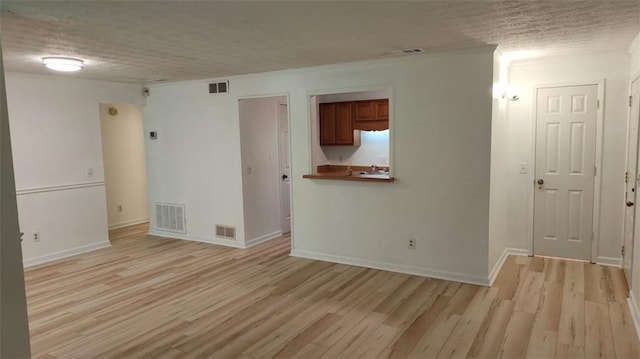 unfurnished room with light wood-style flooring, visible vents, and a textured ceiling