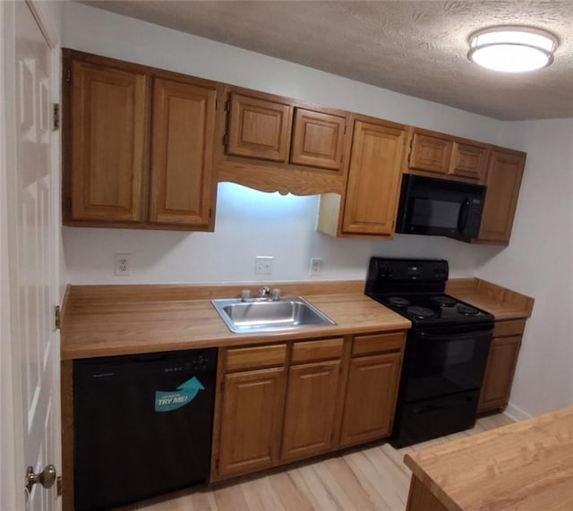 kitchen featuring brown cabinets, a sink, and black appliances