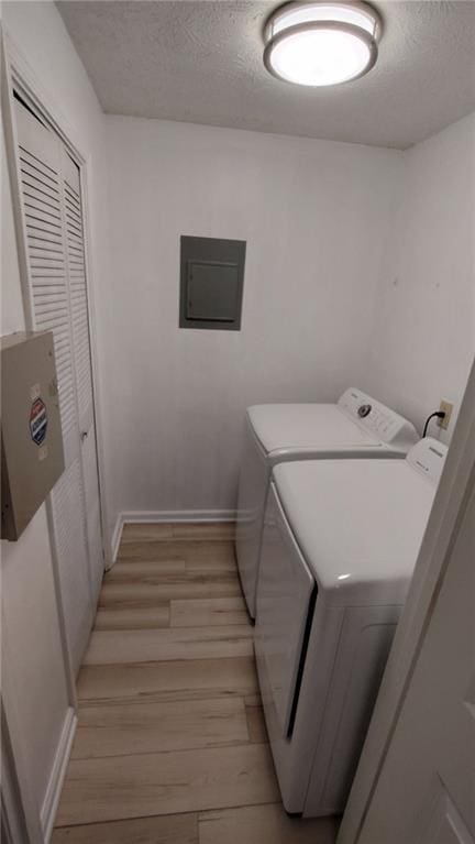 laundry room featuring washer and dryer, a textured ceiling, light wood-type flooring, laundry area, and electric panel