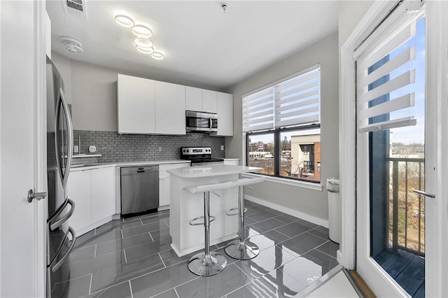 kitchen with white cabinetry, a kitchen island, stainless steel appliances, and a kitchen breakfast bar