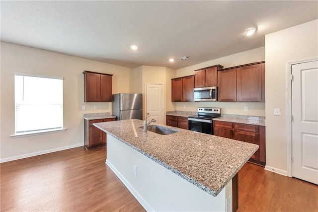 513 Moline Way, Locust Grove, GA 30248 - kitchen featuring appliances with stainless steel finishes, a sink, baseboards, wood finished floors, and a center island with sink