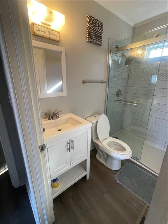 bathroom with hardwood / wood-style flooring, vanity, toilet, and walk in shower