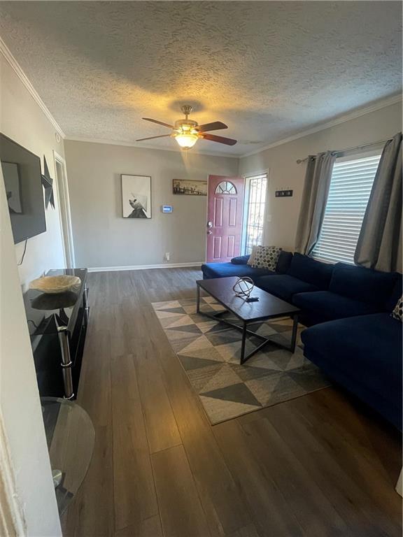 living room featuring crown molding, ceiling fan, dark hardwood / wood-style flooring, and a textured ceiling