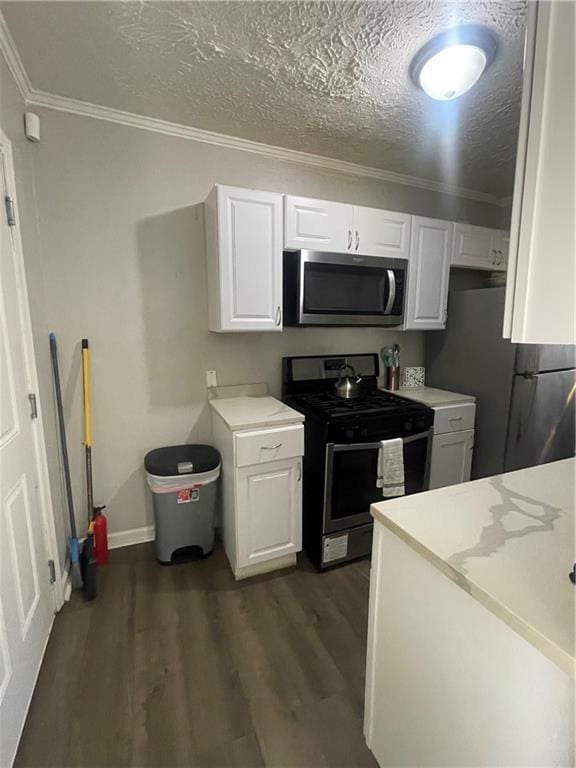 kitchen featuring stainless steel appliances, dark hardwood / wood-style floors, a textured ceiling, white cabinets, and ornamental molding