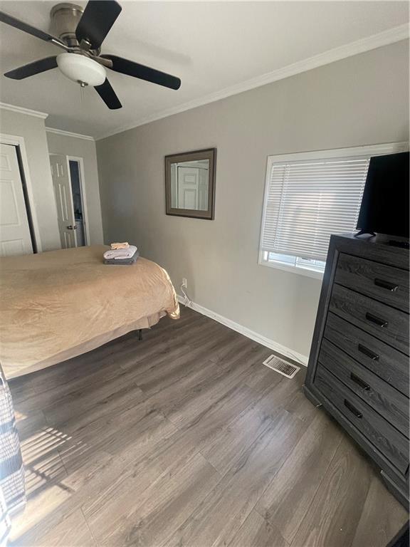 bedroom featuring wood-type flooring, ceiling fan, and crown molding