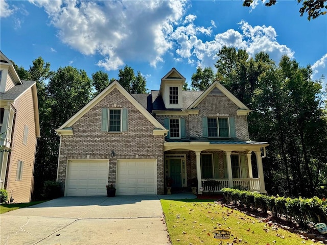 view of front of house featuring covered porch, a garage, and a front yard