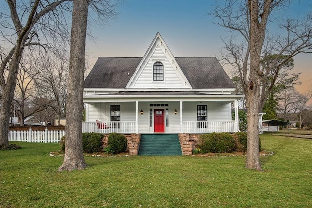 view of front of home featuring covered porch, a shingled roof, fence, and a front yard