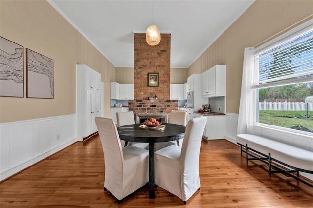 dining area with wainscoting, crown molding, and wood finished floors